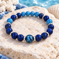 Women's blue stone bead bracelet with silver-tone accents on pale coastal stone